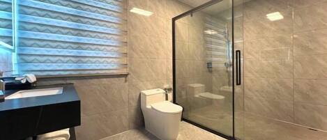 Un baño moderno con inodoro, cabina de ducha de vidrio y tocador con toallero.