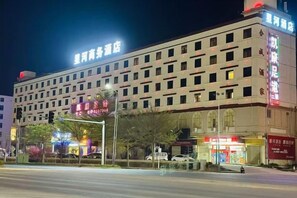 A multi-story hotel with a prominent signage, a covered entrance, and a street view with traffic lights. - Xinghe Business Hotel (Luhe)