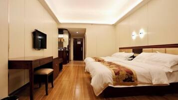 A hotel room with a large bed, a desk, a chair, a television, and a trash bin.