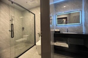 A modern bathroom with a glass-enclosed shower, a white toilet, and a black sink with a mirror above it. - Xinghe Business Hotel (Luhe)