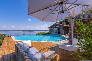 A wooden deck with wicker furniture and a pool overlooking a scenic view of the sea. - Paradis Relais Pool View EV Recharge (Belgirate)