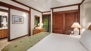 A hotel room with a bed, a nightstand with a lamp, a dresser, a mirror, and a window with shutters. - Kiahuna Plantation Resort 190 Ocean View 1 Bedroom (Koloa)