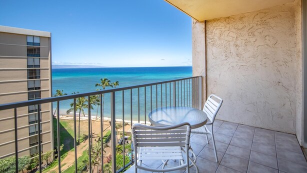 Ein Balkon mit Blick auf den Ozean, ein weißer Stuhl und ein kleiner Tisch.