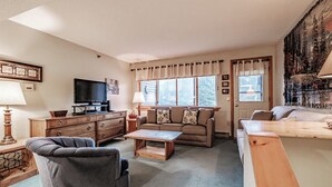 A cozy living room with a sofa, coffee table, and TV. - One Bedroom Cascades A-24, direct access from outside, sleeps 6 (Newry)