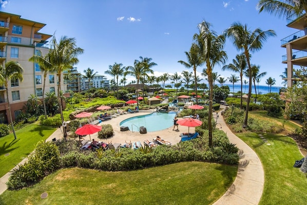 A resort pool area with a curved pool, palm trees, and lounge chairs.