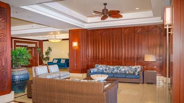 A spacious lobby with a large wicker sofa, a blue sofa, and a floor lamp. There is a ceiling fan and a large potted plant. - Honua Kai Ocean View 3Bedroom 3Bath (Lahaina)
