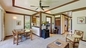 A spacious living area with a dining table, chairs, a coffee table, and a fireplace. - Kiahuna Plantation Resort Ocean View 1 Bedroom (Koloa)