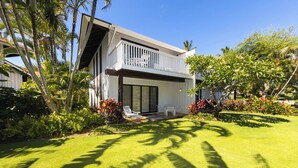 A modern two-story house with a balcony, surrounded by lush greenery and palm trees. - Kiahuna Plantation Resort Ocean View 1 Bedroom (Koloa)