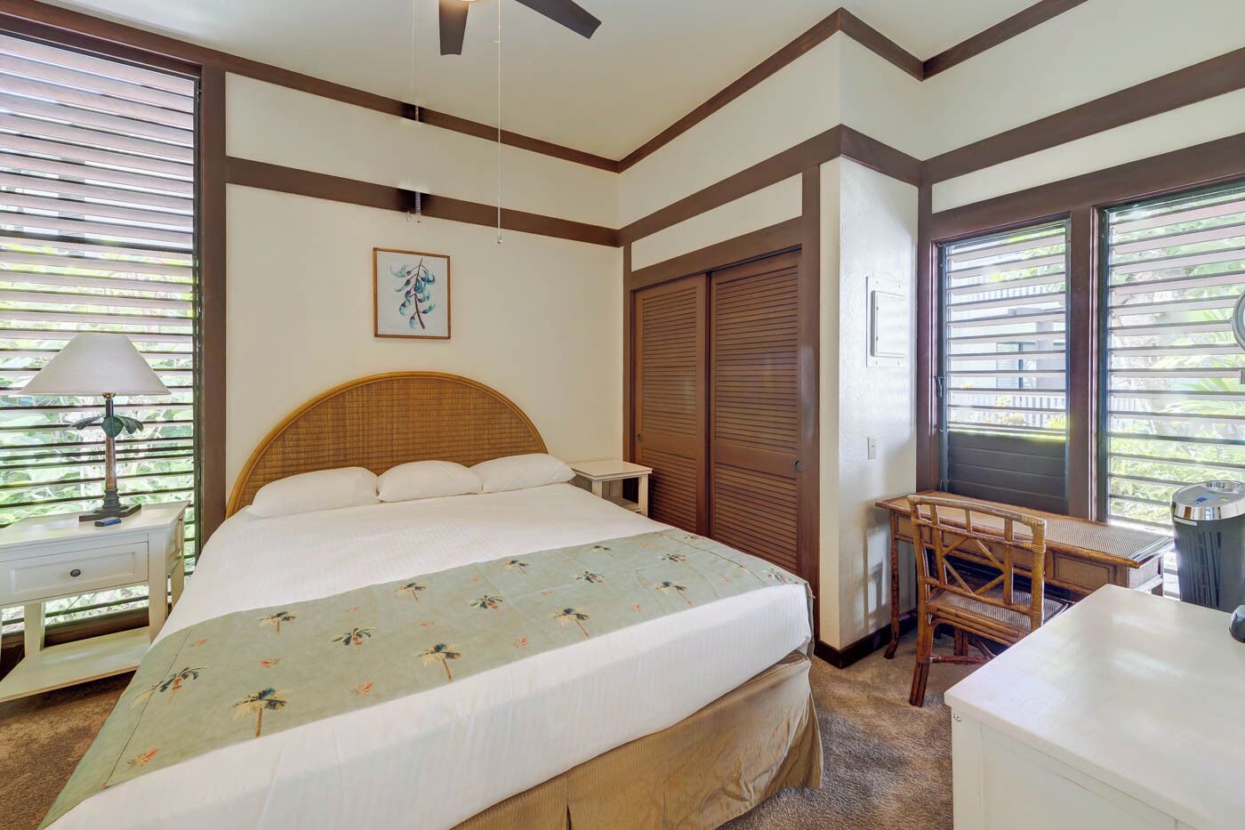 A bedroom with a bed, bedside table, lamp, wardrobe, and a desk with chair.