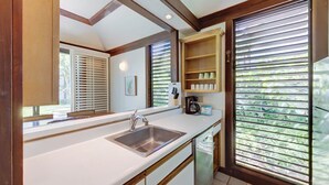 A kitchen with a sink, a coffee maker, and a window with blinds. - Kiahuna Plantation Resort Ocean View 1 Bedroom (Koloa)