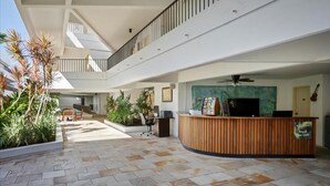 A spacious lobby with a reception desk, seating area, and a staircase leading to an upper level. - Royal Sea Cliff Kona Studio (Kailua Kona)