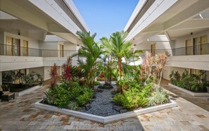 Un atrium à plusieurs niveaux, doté d’un jardin central agrémenté de diverses plantes tropicales et d’un sentier en gravier.