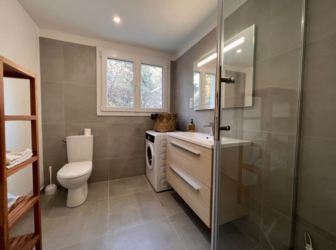 Un baño moderno con inodoro, lavadora y cabina de ducha de vidrio.