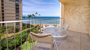 Un balcon avec vue sur la plage, une table ronde et une chaise.