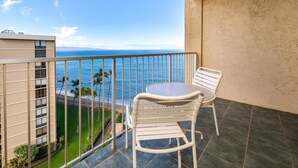 Un balcon avec vue sur l’océan, une table et deux chaises.