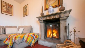 A cozy living room with a fireplace, a sofa, and a colorful throw blanket. - Charming Villa I Tre Archi (Pisano)