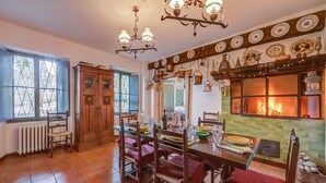 A dining area with a wooden table, chairs, and a fireplace. - Charming Villa I Tre Archi (Pisano)