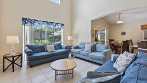 A spacious living room with two sofas, a coffee table, and a dining area with chairs and a table.