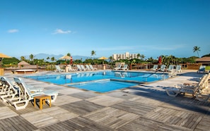 A pool area with multiple lounge chairs and a wooden deck.