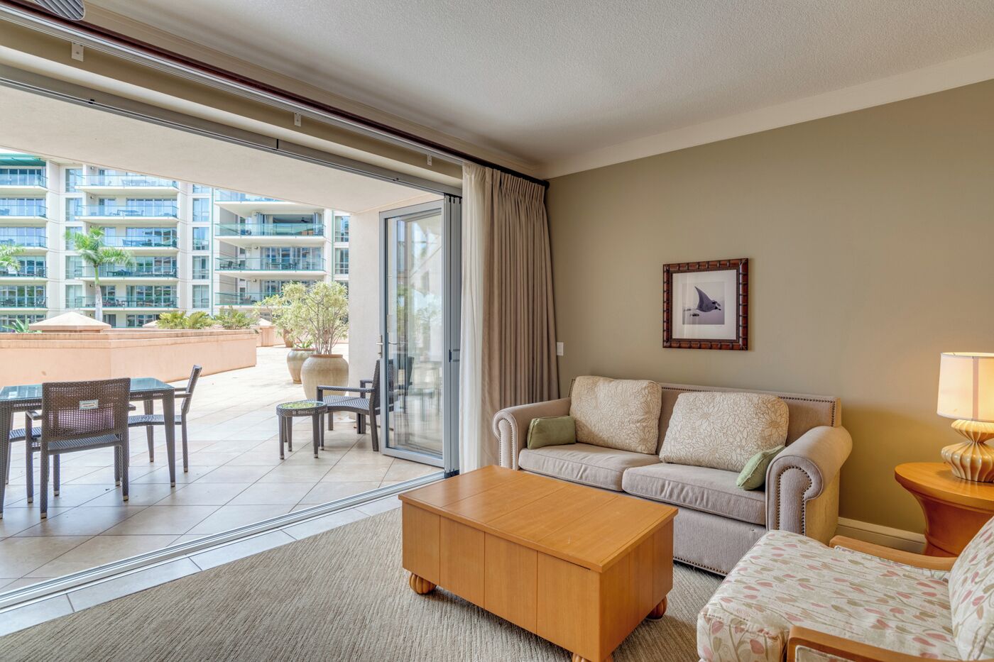 A hotel room with a sofa, armchair, coffee table, and a dining area with chairs and a table.