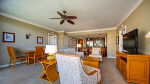 A living room with a sofa, chairs, a TV, and a ceiling fan.