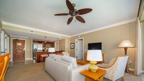 A hotel room with a living area, kitchenette, and a ceiling fan.
