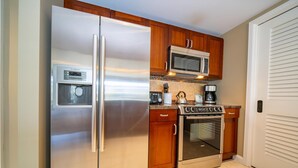 A kitchen with stainless steel appliances, wooden cabinets, a microwave, and an oven.