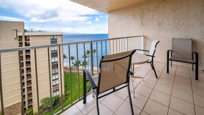 A balcony with a view of the ocean, a chair, and a table. - Royal Kahana Maui 1218 Ocean View Studio (Lahaina)