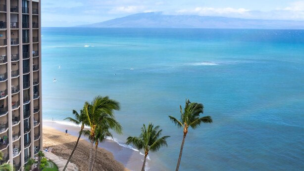 A high-rise hotel overlooking a beach with clear blue water and palm trees. - Royal Kahana Maui 1218 Ocean View Studio (Lahaina)