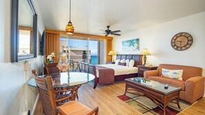 Une chambre d’hôtel comprenant un lit, un canapé, une table à manger avec des chaises, un balcon avec vue et une horloge au mur.