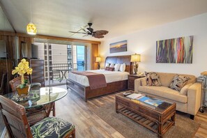 Une chambre d’hôtel comprenant un lit, un canapé, une table à manger avec des chaises, un balcon et un tableau au mur.