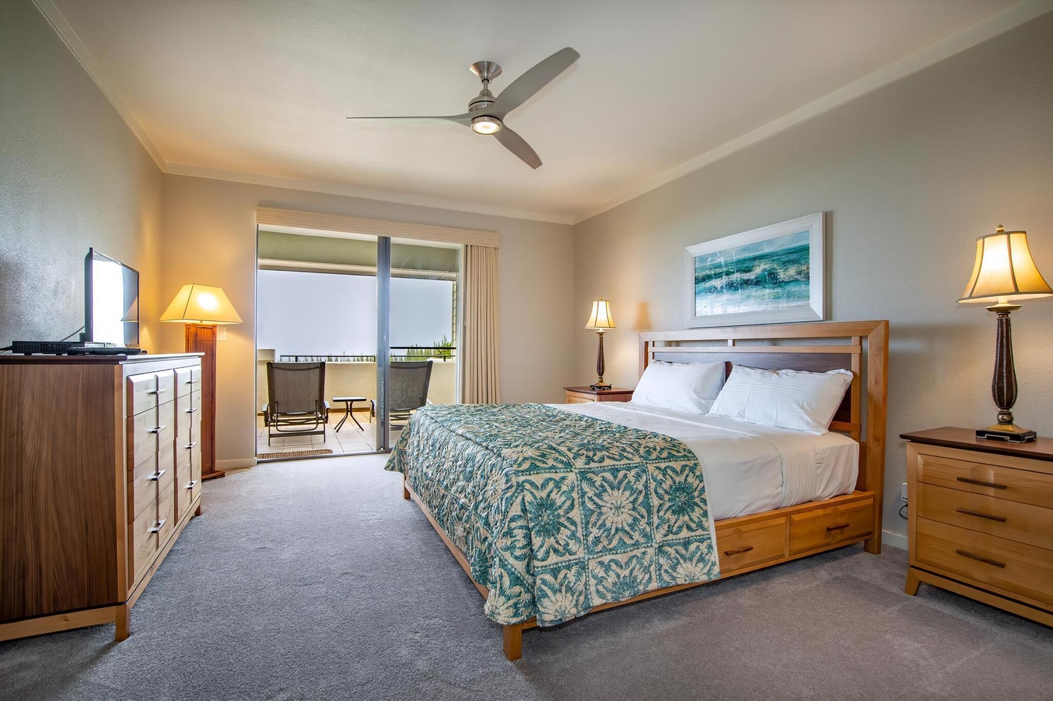 A bedroom with a bed, a desk, a chair, a ceiling fan, and a balcony with a chair.