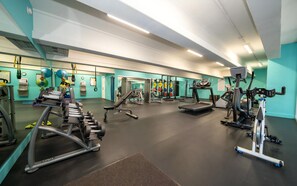 Et fitnessrum med forskellig træningsudstyr, herunder løbebånd, styrkemaskiner og håndvægte.