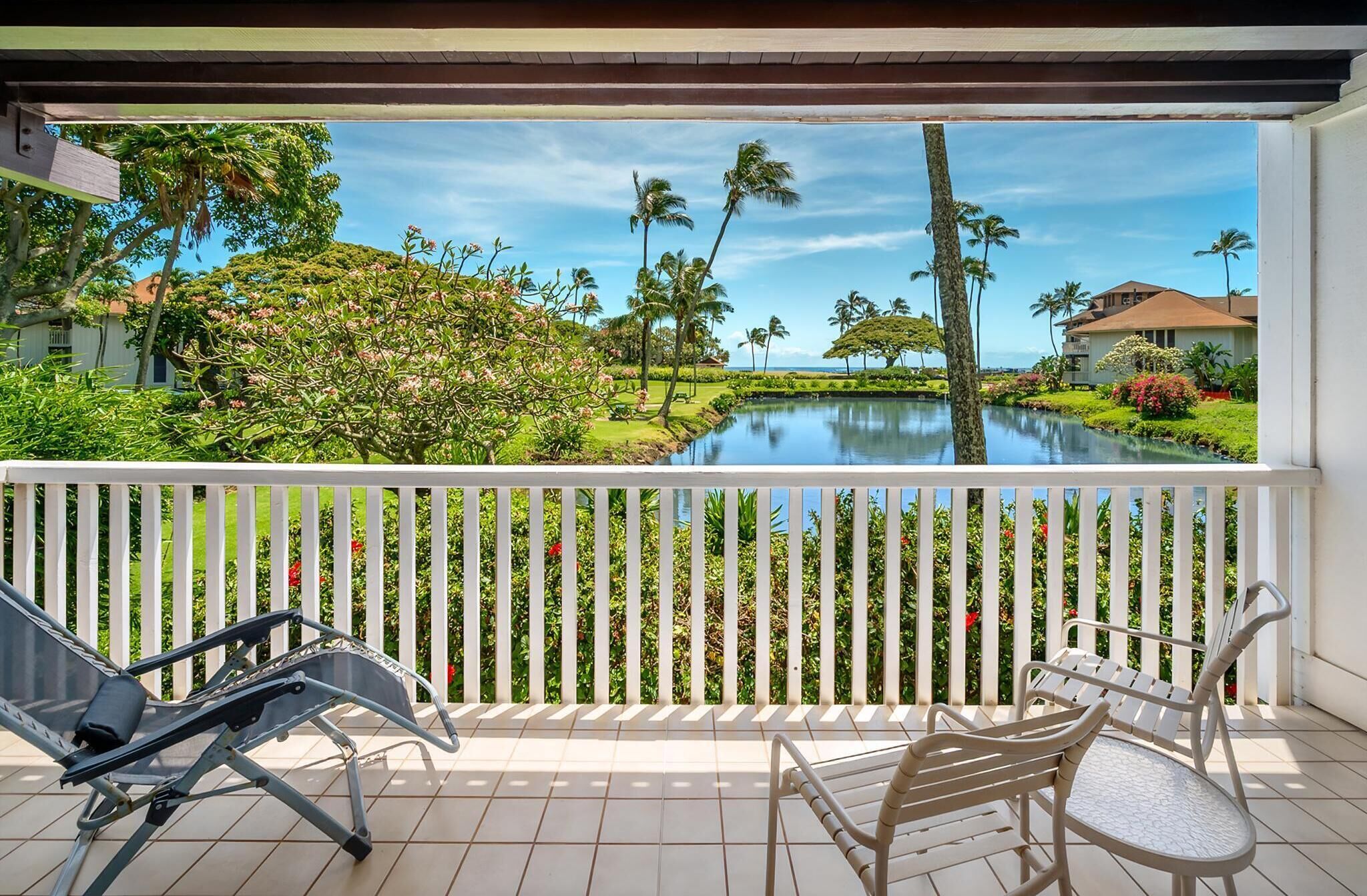 A balcony with a view of a lake, surrounded by lush greenery and palm trees.