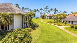 A golf course with a well-maintained lawn, palm trees, and buildings with a traditional architectural style.