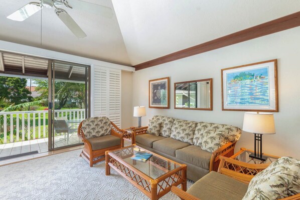 A living room with a glass door leading to a balcony, a sofa, two armchairs, a coffee table, and wall-mounted lamps.