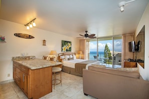 A hotel room with a bed, a dining area, a balcony with a view, and a TV.