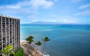Un hôtel de grande hauteur doté de balcons donnant sur une plage et l’océan.