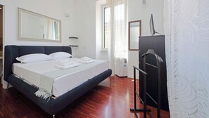 A bedroom with a bed, a mirror, a wardrobe, and a window with curtains. - 4BNB - Angelo Emo - One Bedroom Apartment, Sleeps 5 (Rome)