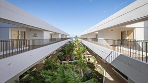 A modern hotel corridor with a central garden, white walls, and balconies. - Royal Sea Cliff Kona 429 Partial Ocean View Studio (Kailua Kona)