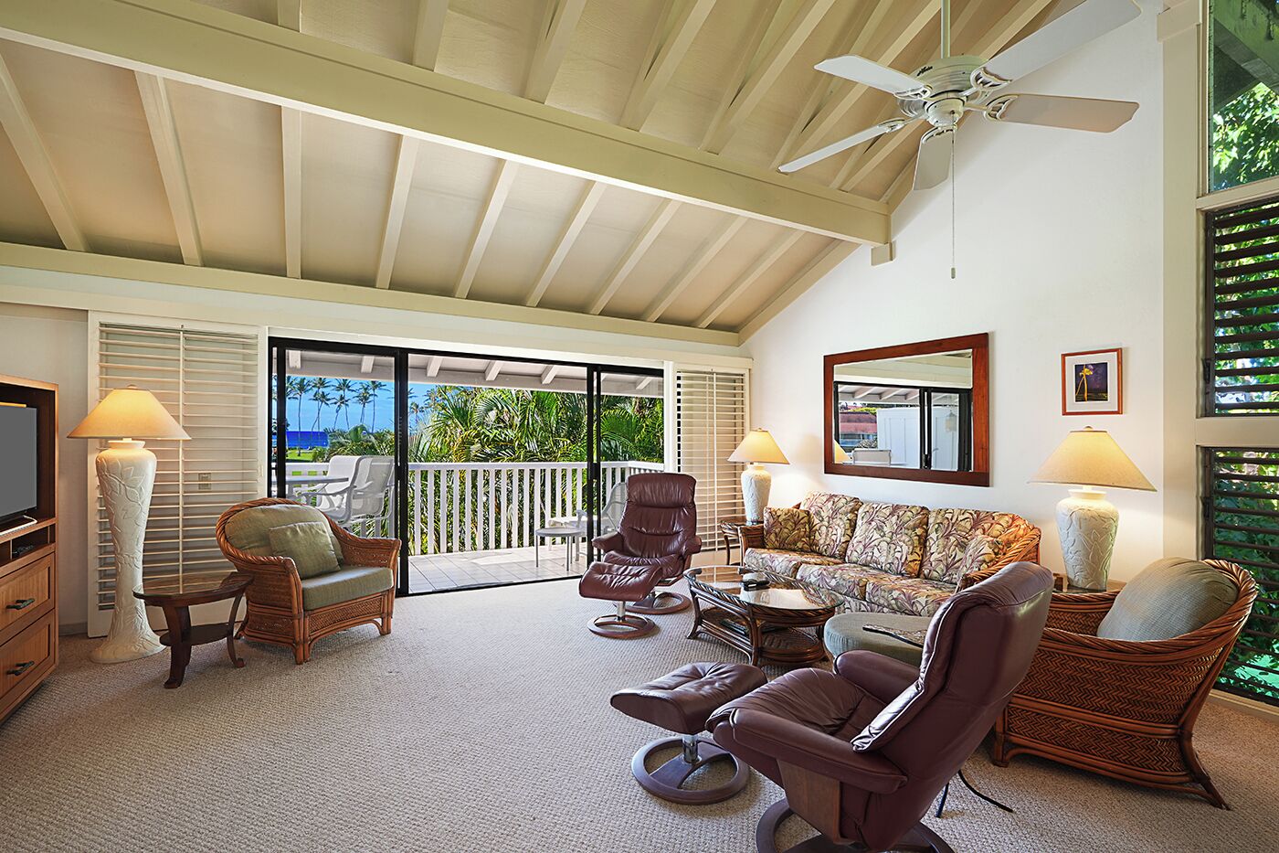 A spacious living area with a ceiling fan, a sofa, chairs, a television, and a view of the outdoors.