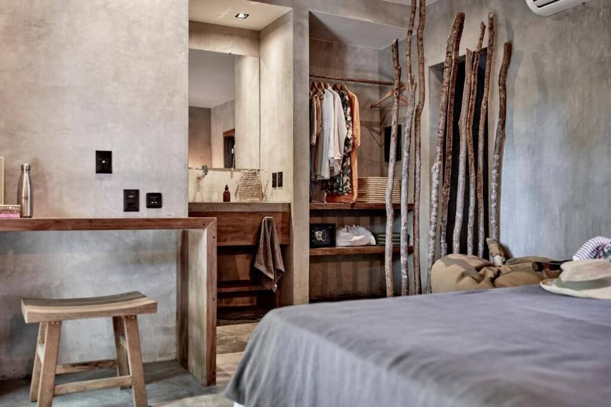 Une chambre à coucher moderne avec un grand lit, un tabouret en bois, une armoire et un miroir.