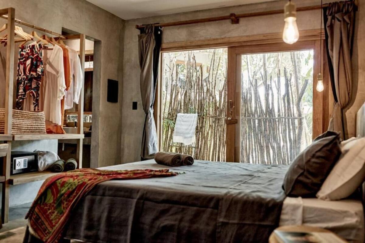 Une chambre avec un lit, une armoire et une vue sur des bambous à l’extérieur.