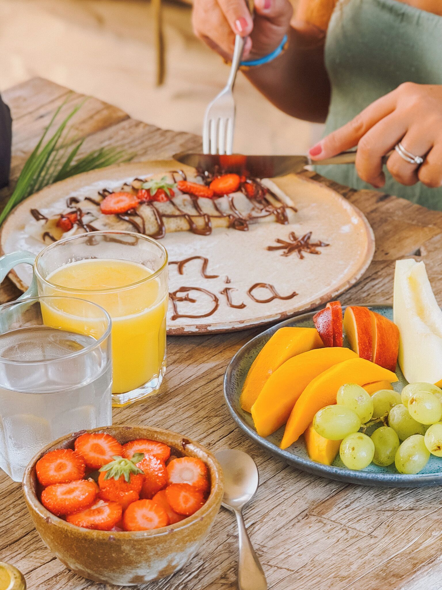 A breakfast setting with a plate of food, a bowl of strawberries, a glass of orange juice, and a plate of fruits.