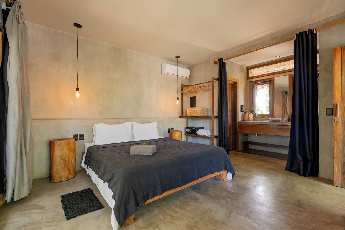 Une chambre moderne avec un grand lit, des tables de chevet en bois, un luminaire suspendu et une armoire intégrée.