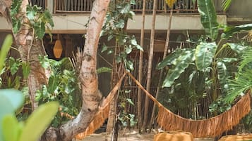 Una hamaca en un jardín exuberante, con un edificio al fondo.