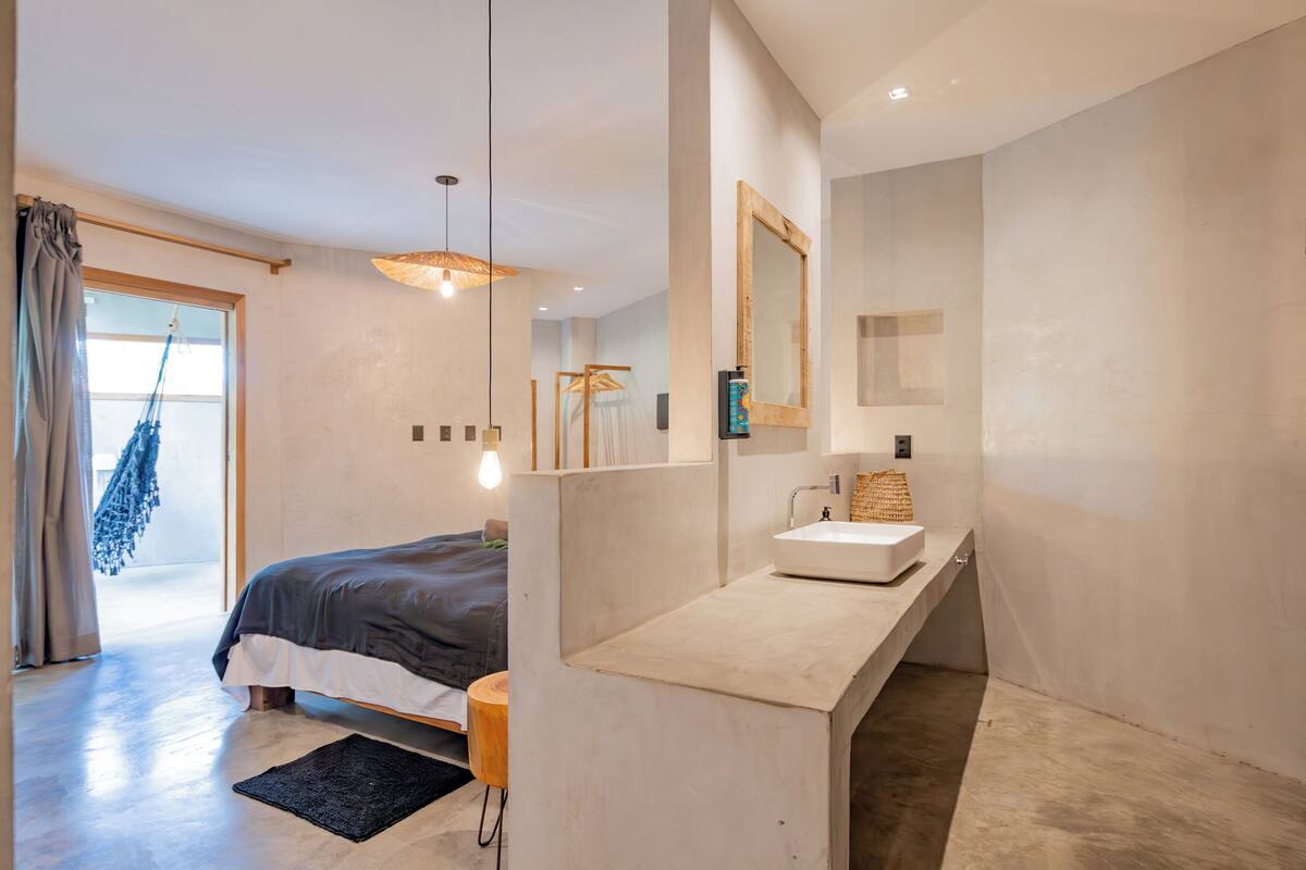 Une chambre moderne avec un grand lit, une table de chevet, un lavabo intégré et un grand miroir.