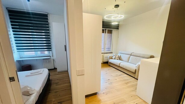 Een knus woongedeelte met een bed, een slaapbank en een kleine kitchenette.