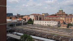 Een treinstation met meerdere sporen en een groot gebouw met een groene koepel op de achtergrond.