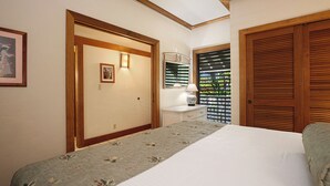 Un dormitorio con cama, mesita de noche, lámpara, puerta y ventana con persianas.